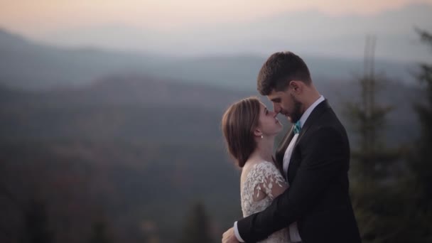 Recién casados. novio caucásico con novia en la ladera de la montaña. Pareja de bodas. Feliz. — Vídeo de stock