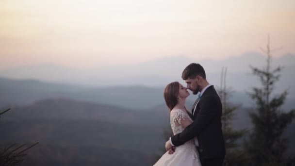 Recién casados. novio caucásico con novia en la ladera de la montaña. Pareja de bodas. Feliz. — Vídeos de Stock