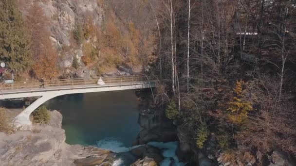 Recém-casados. Noiva e noivo em uma ponte sobre um rio de montanha. Vista aérea — Vídeo de Stock