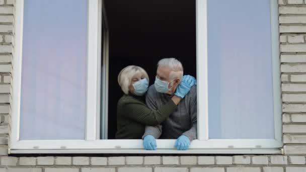 Los abuelos viejos se quedan en la ventana aislados en casa en cuarentena. Coronavirus — Vídeos de Stock