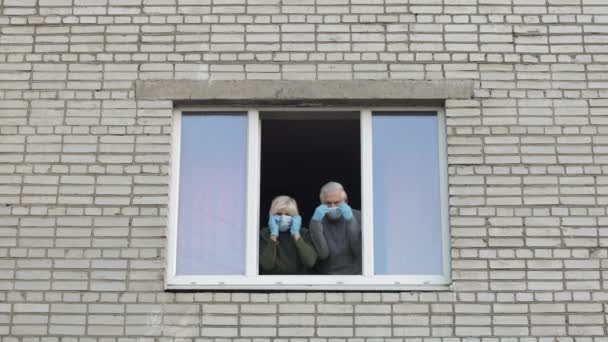Az öreg nagyszülők otthon maradnak az ablakban, elkülönítve a karanténban. Koronavírus — Stock videók