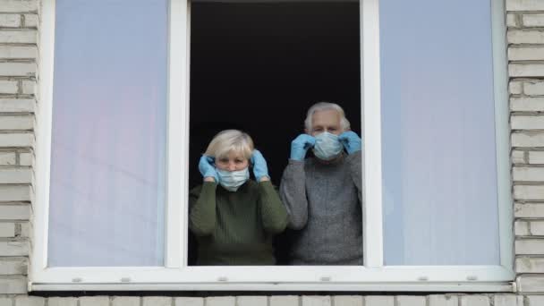 Les vieux grands-parents restent à la fenêtre isolés à la maison en quarantaine. Coronavirus — Video