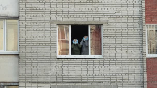 Les vieux grands-parents restent à la fenêtre isolés à la maison en quarantaine. Coronavirus — Video