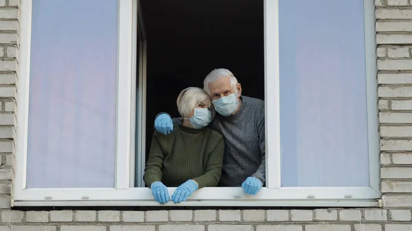 Los abuelos viejos se quedan en la ventana aislados en casa en cuarentena. Coronavirus — Foto de Stock