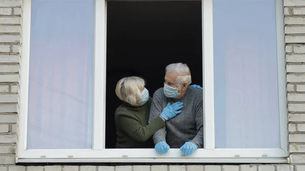 Az öreg nagyszülők otthon maradnak az ablakban, elkülönítve a karanténban. Koronavírus — Stock Fotó