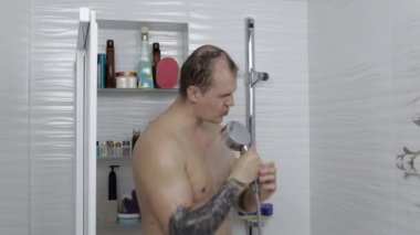 Genç ve yakışıklı şişman adam banyoda duş alıyor. Duygusal olarak şarkı söyler ve dans eder