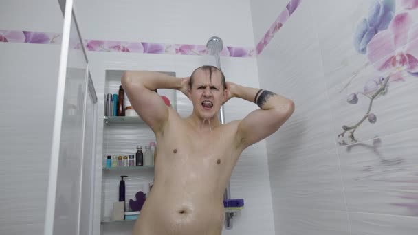 Jonge knappe dikke man neemt een douche in de badkamer. Emotioneel zingt en danst — Stockvideo