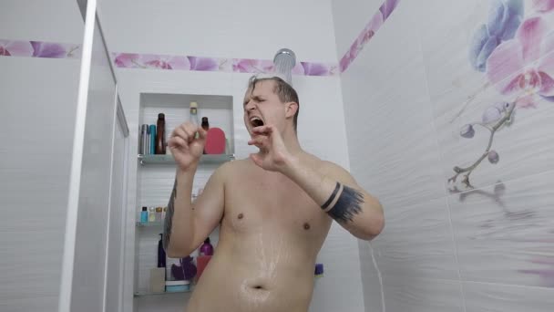 Jonge knappe dikke man neemt een douche in de badkamer. Emotioneel zingt en danst — Stockvideo