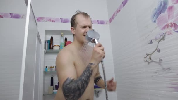 Junge hübsche dicke Mann nimmt eine Dusche im Badezimmer. Emotional singt und tanzt — Stockvideo