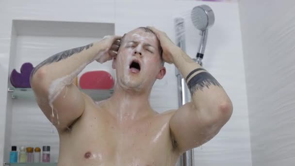 Jóképű izmos férfi zuhanyozik a fürdőszobában. Érzelmileg énekel és táncol — Stock videók