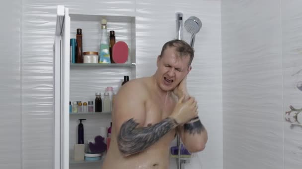 Joven hombre gordo guapo toma una ducha en el baño. Emocionalmente canta y baila — Vídeo de stock