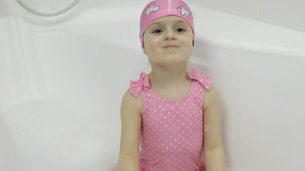 Linda chica rubia toma un baño en traje de baño. Niño pequeño jugar en el baño — Foto de Stock