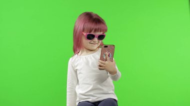 Akıllı telefon kullanan bir kız. Çocuk cep telefonuyla duygusal konuşuyor, selfie çekin.