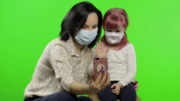 Moeder, dochter met medisch masker met smartphone in gesprek op video — Stockfoto