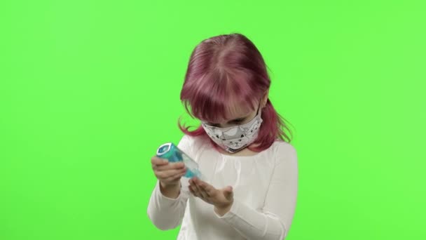 Mała dziewczynka w masce medycznej. Używa środka do dezynfekcji rąk. COVID-19 Koronawirus — Wideo stockowe
