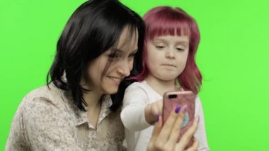 Annesi, kızı elinde tutuyor, video konuşmasında akıllı telefon kullanıyor. Sosyal medya