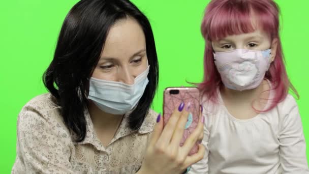 Mother, daughter wearing medical mask holding smart phone talking on video call — Stock Video