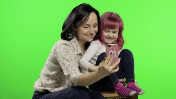 Madre, hija sosteniendo, usando el teléfono inteligente hablando en video llamada. Redes sociales — Vídeo de stock
