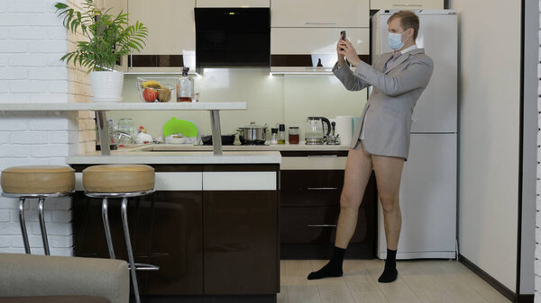 Карантин. Бизнесмен в маске работает по телефону в домашнем офисе. Коронавирус
