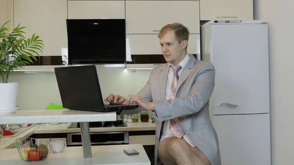 Üzletember nyakkendőben és zakóban, laptopon dolgozik az otthoni irodában. Távoli munka — Stock Fotó
