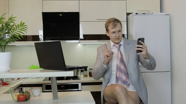 ネクタイとジャケットのビジネスマンは自宅でスマートフォンでオンラインでビデオチャットを持っている — ストック写真