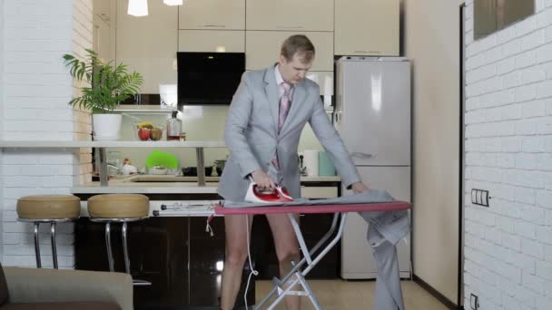 Όμορφος επιχειρηματίας με γραβάτα, σιδερώνει παντελόνια στο σπίτι. προετοιμασία της συνεδρίασης — Αρχείο Βίντεο