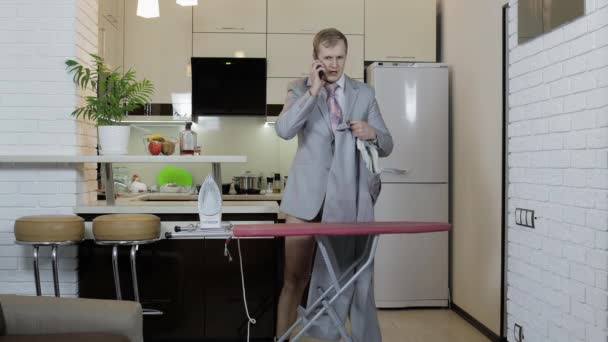 Όμορφος επιχειρηματίας με γραβάτα, σιδερώνει παντελόνια στο σπίτι. προετοιμασία της συνεδρίασης — Αρχείο Βίντεο