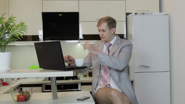 Kravatlı ve ceketli bir iş adamı ev ofisinde dizüstü bilgisayarla çalışıyor. Uzak çalışma — Stok video