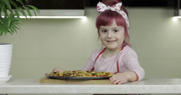 Vařím pizzu. Malé dítě v zástěře s čerstvě upečenou horkou pizzou v kuchyni — Stock video