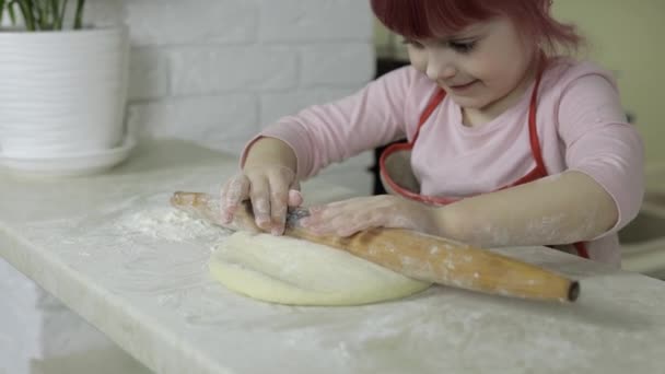 Cocinar pizza. Pequeño niño en delantal rollo de masa con rodillo en casa cocina — Vídeos de Stock