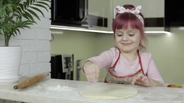Pizza pişiriyorum. Önlüklü küçük çocuk mutfağa un serp.