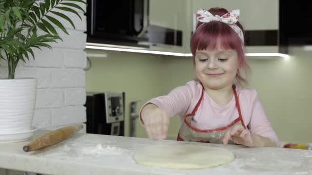 ピザを作る。エプロンの小さな子供は、台所で小麦粉で生地を振りかける — ストック動画