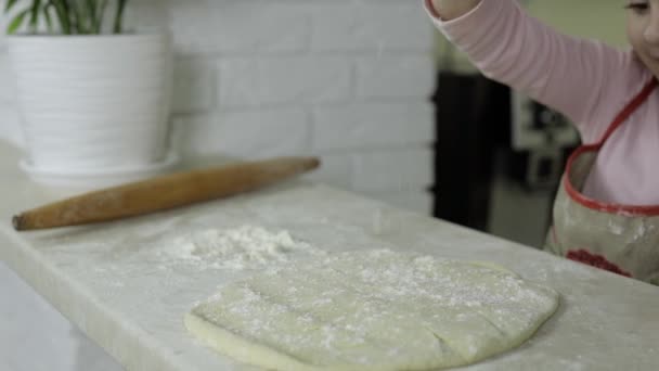 ピザを作る。エプロンの小さな子供は、台所で小麦粉で生地を振りかける — ストック動画