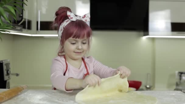 Pizza kochen. Kleines Kind in Schürze bereitet Teig für das Kochen in der heimischen Küche zu