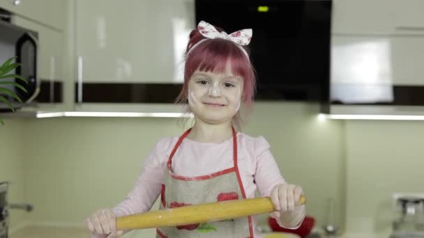 Liten flicka i köket klädd i förkläde och halsduk med rullande stift — Stockvideo