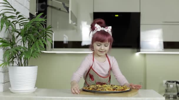 Pizza koken. Klein kind in schort met vers gebakken hete pizza in de keuken — Stockvideo