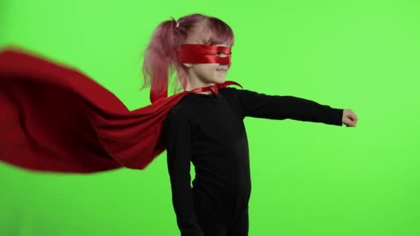 Roliga barn flicka i kostym och mask spelar super hjälte. Nationell superhjältedag — Stockvideo