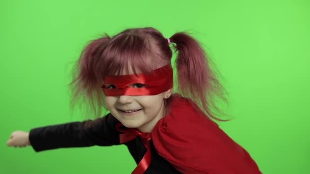 Grappig kind meisje in kostuum en masker speelt super held. Nationale superheldendag — Stockvideo