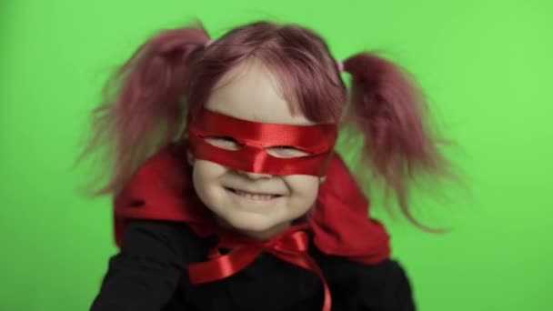 Roliga barn flicka i kostym och mask spelar super hjälte. Nationell superhjältedag — Stockvideo