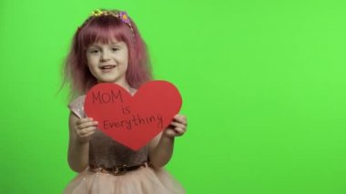 Çocuk prenses, annesi hakkında yazılan mesajlarla kırmızı kağıt kalbi tutuyor. Anneler Günü