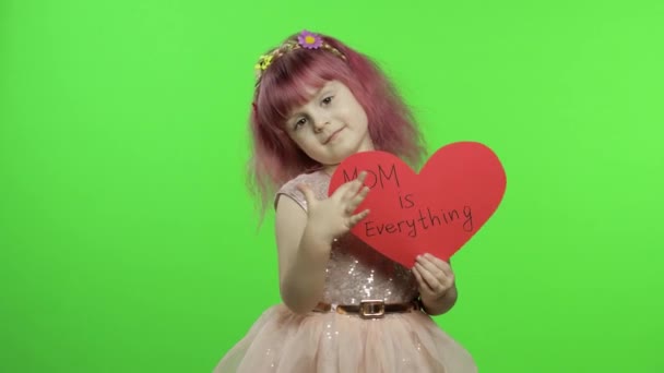 Çocuk prenses, annesi hakkında yazılan mesajlarla kırmızı kağıt kalbi tutuyor. Anneler Günü — Stok video