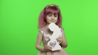 Kız, ahşap fotoğraf çerçevesini hamile bir kadın şeklinde tutuyor. Anneler Günü