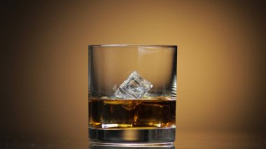 Alkol viski içer, konyak bardağa buz küpleri koyar. Koyu arkaplan.