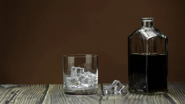 Το αλκοόλ πίνει ουίσκι, το κονιάκ σε ποτήρι με πάγο. Φιάλη μισογεμάτη στο τραπέζι — Φωτογραφία Αρχείου