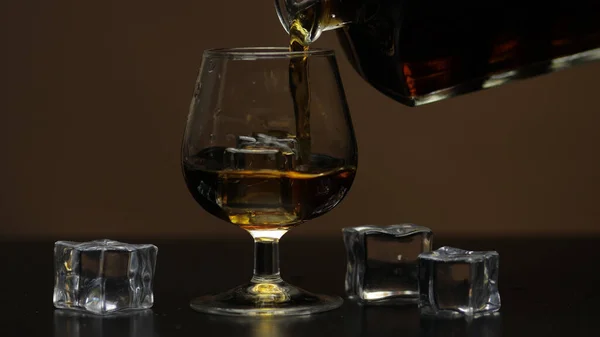 Налить виски, коньяк в стакан. Коричневый фон Наливка алкогольного напитка — стоковое фото