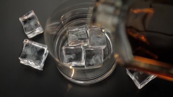 Pouring whiskey, cognac into glass with ice cubes. Pour of alcohol drink — Stock Video