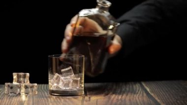Viski ve konyağı cama döküyorum. Siyah arka plan. Alkol içeceği.
