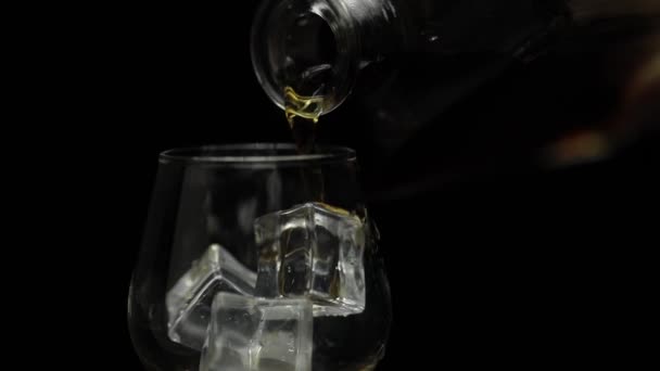 Derramando álcool beber uísque, conhaque em vidro. Fundo preto. Movimento lento — Vídeo de Stock