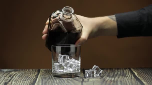 Pouring whiskey, cognac into glass. Dark background. Pour of alcohol drink — Stock Video