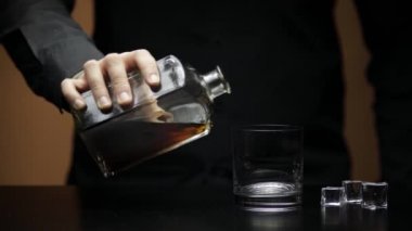 Viski, konyak ve buz küpleri. Barmen içki doldurur.